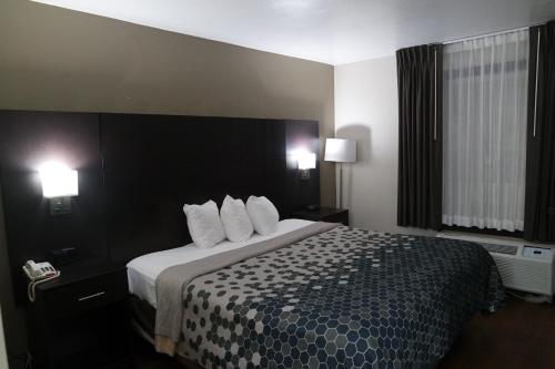 a hotel room with a large bed with white pillows at Travelodge by Wyndham North Charleston in Charleston