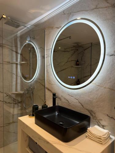 Un baño con un lavabo negro y un espejo. en Luxy renovated flat with patio, en Atenas