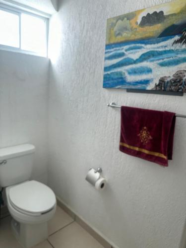 a bathroom with a toilet and a painting on the wall at Casa Lisboa in Puerto Vallarta