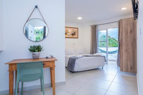 ein Schlafzimmer mit einem Schreibtisch, einem Bett und einem Spiegel in der Unterkunft Pousada Cahê in Ilhabela