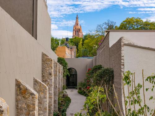a walkway between two buildings with a church in the background at Paseo del Centro, Condominio Boutique in San Miguel de Allende