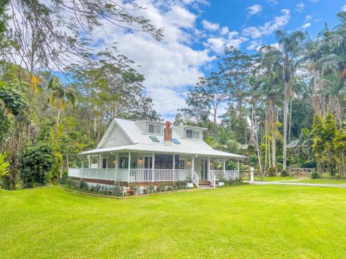 een groot wit huis met een grote tuin bij The Gingerbread House in Upper Tallebudgera