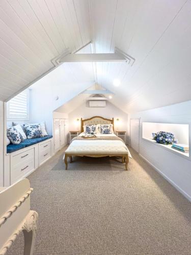 a bedroom with a large bed and two windows at The Gingerbread House in Upper Tallebudgera
