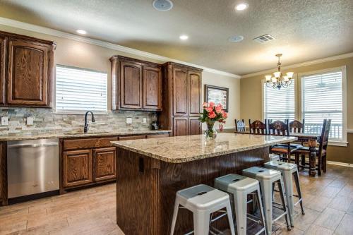 een keuken met houten kasten en een groot eiland met barkrukken bij River Ridge on the Guadalupe - Riverfront with Large Deck, Direct Float Access & Cliff Side Views in New Braunfels