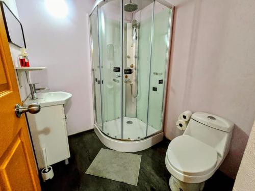 a bathroom with a toilet and a glass shower at Suite Naranja moderna para 3 huéspedes Cocina equipada, Wi-Fi rápido y excelente ubicación céntrica in Mexico City