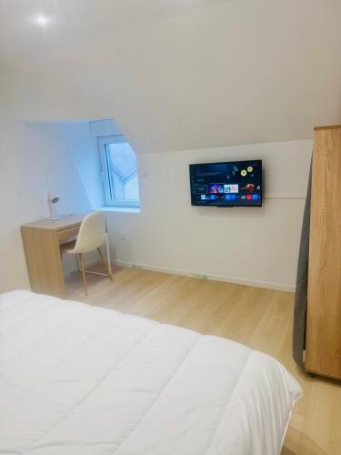 a bedroom with a bed and a desk with a tv on the wall at wihi-loges - Appartement type grand T2, calme, centre-ville de Nevers in Nevers
