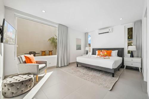 ein weißes Schlafzimmer mit einem Bett und einem Stuhl in der Unterkunft DayDream Villa in Palm-Eagle Beach