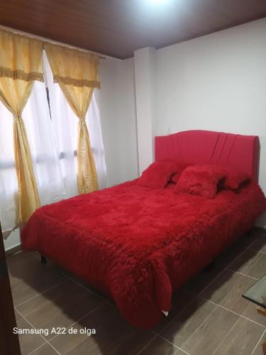 een groot rood bed in een kamer met een raam bij Casa punta del este in Paipa