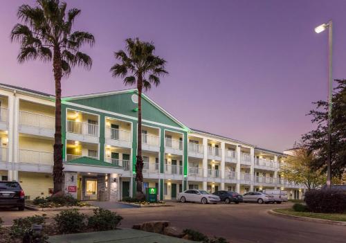 a large building with cars parked in a parking lot at HomeTowne Studios by Red Roof Houston - Northwest in Houston