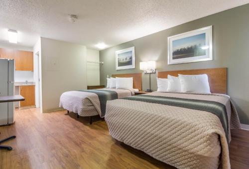 a hotel room with two beds and a television at HomeTowne Studios by Red Roof Houston - Northwest in Houston