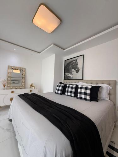ein Schlafzimmer mit einem großen Bett mit schwarzen und weißen Kissen in der Unterkunft Bela casa em Guaratiba in Mato Alto