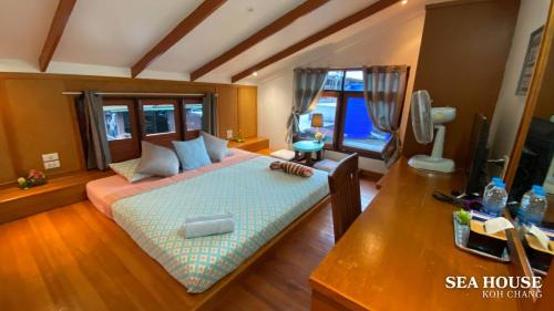 a bedroom with a bed and a desk with a television at Sea House Koh Chang in Ko Chang