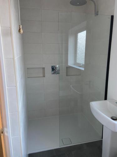 a shower with a glass door next to a sink at Comfortable Homestay by Earith Lakes in Earith