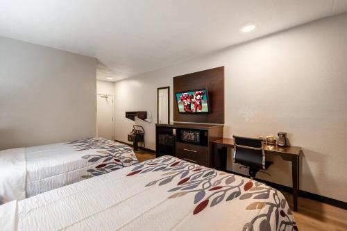 Una habitación de hotel con dos camas, un escritorio y un televisor. en Red Roof Inn Tucson North - Marana, en Tucson