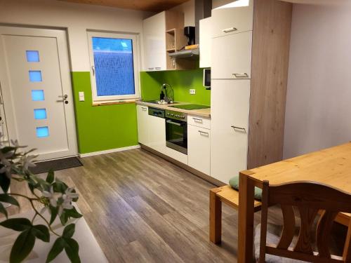 cocina con paredes verdes, armarios blancos y mesa en Nature Fun Apartments - Ruhige Lage nahe Pressegger See - Skibus zum Nassfeld - Familien & Hunde willkommen, en Hermagor