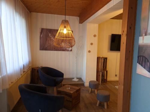 a living room with blue chairs and a chandelier at Ferienwohnung am Hotel "Mein Bergblick" in Goslar