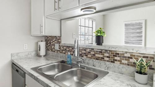 eine Küche mit einer Spüle aus Edelstahl und weißen Schränken in der Unterkunft Landing Apartments - Denton in Denton