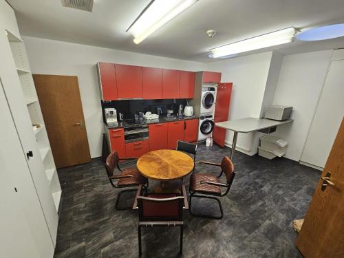 a kitchen with red cabinets and a table and chairs at Privat Grosse Zimmer, Mars, mit gemeinsamer Küche und Bad in Altstadt Chur in Chur