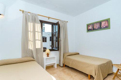 a bedroom with two beds and a window at Apartamentos Posidonia in Son Parc