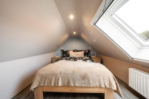una camera mansardata con letto e lucernario di Küsten Suite Burghaus 5, 60qm a Krummhörn