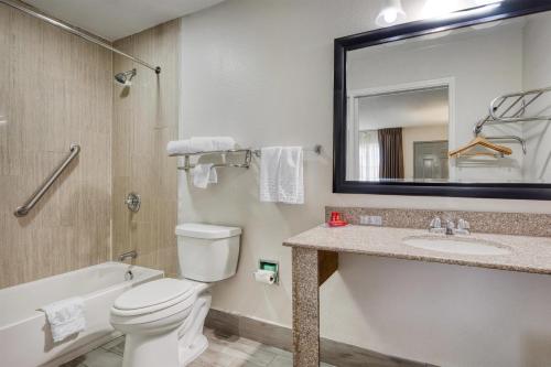 a bathroom with a toilet and a sink and a mirror at SureStay Hotel by Best Western Terrell in Terrell