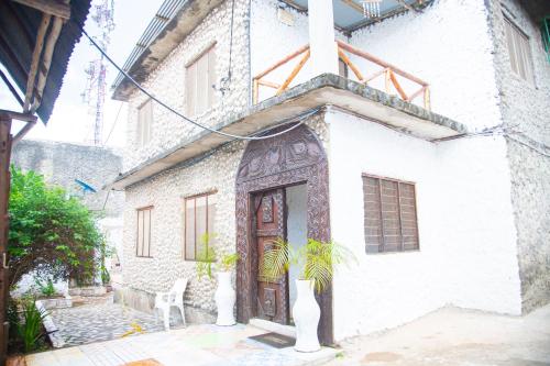 un edificio blanco con una puerta de madera y una planta en Spice Garden Lodge B&B, en Zanzíbar