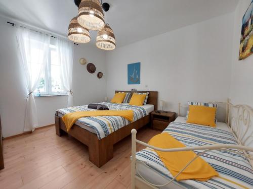 two beds in a room with white walls and wooden floors at House House Jadranovo in Jadranovo
