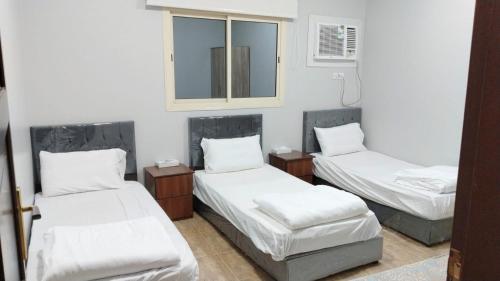 een kamer met 3 bedden en een spiegel bij شقق الفتح الخاصة Al Fath Private Apartments in Al Madinah