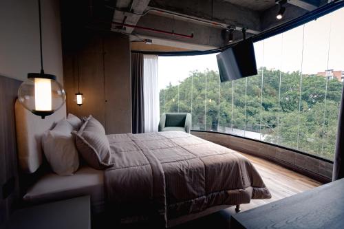 a bedroom with a bed and a large window at Uukam by Bernalo Hotels in Medellín