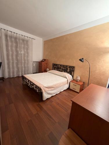 a bedroom with a bed and a lamp on a wooden floor at La casa di Alice in Orbassano