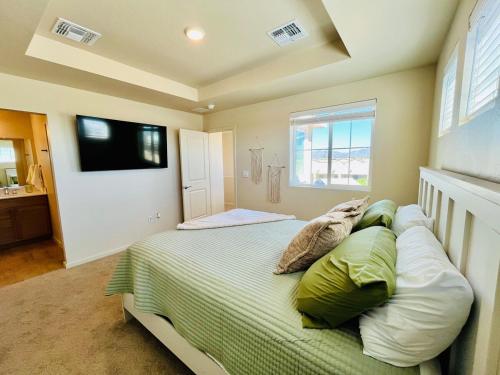 een slaapkamer met een bed met kussens en een televisie bij Organ Mountain Loft 3BR 3 Steps into Golf Course in Las Cruces