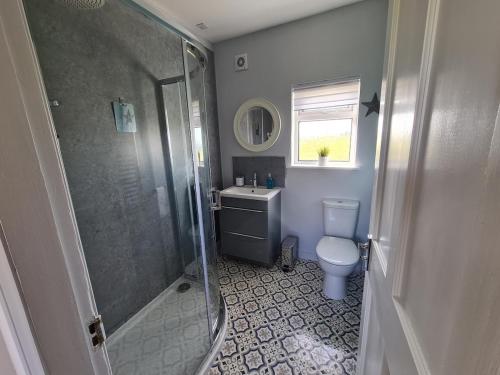 een badkamer met een douche, een toilet en een wastafel bij Beachcroft Cottage in Aird Tong