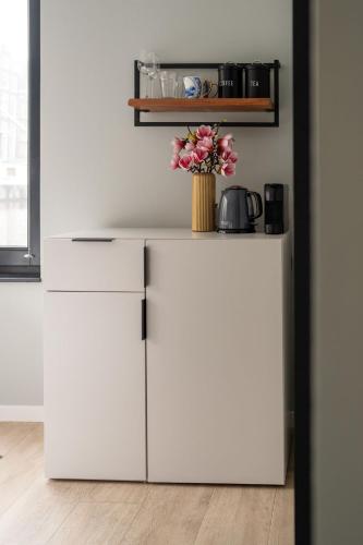 a white refrigerator with a vase of flowers on top at 2 Houseboat Suites Amsterdam Prinsengracht in Amsterdam