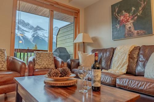a living room with a couch and a table with wine glasses at Rundle Range Retreat Lux Mtn View Condo near dt in Canmore
