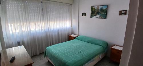 een kleine slaapkamer met een groen bed en een tafel bij Frente al mar in Miramar
