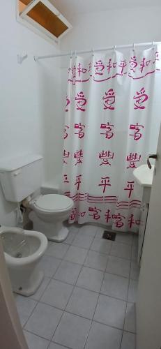 a bathroom with a toilet and a shower curtain at Frente al mar in Miramar