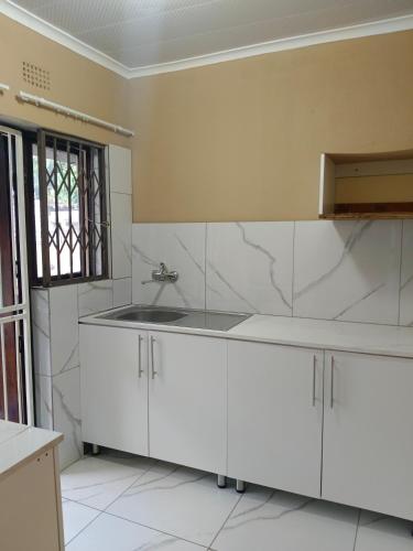 a kitchen with white cabinets and a sink at The Glen House in Durban