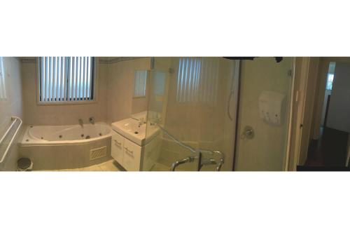 a bathroom with a shower and a tub and a sink at Yerrabi Pond in Hall