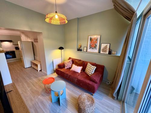 Una sala de estar con un sofá rojo y una cocina. en Grand RDC 6 Pers Arras Stationnement gratuit, en Arras