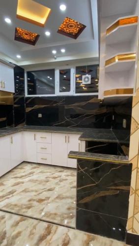 una cucina con mobili bianchi e ripiani neri di Madina plaza a Kabul