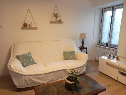 a living room with a white couch and a table at Le gîte des Bernadettes in Apchat