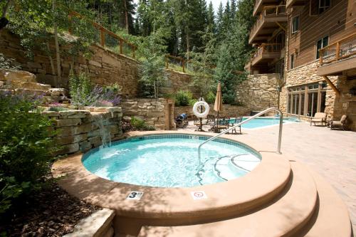 una bañera de hidromasaje en un patio con una pared de piedra en Timbers & Lone Eagle by Keystone Resort en Keystone