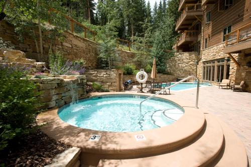 - un bain à remous dans une cour dotée d'un mur en pierre dans l'établissement Timbers & Lone Eagle by Keystone Resort, à Keystone