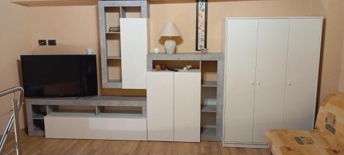 un soggiorno con una TV e un mobile bianco di Loft Mansardato a Catania