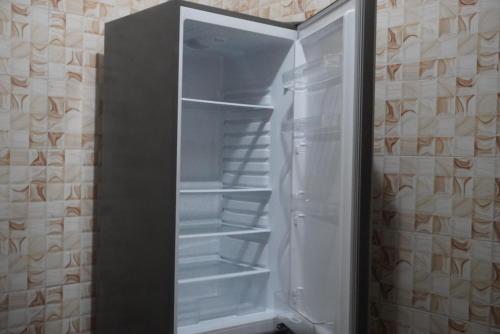 Un refrigerador vacío con la puerta abierta en una cocina. en Villa cosy - Angré soleil 2, en Abiyán