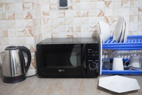 un microondas negro sentado en un mostrador junto a una cafetera en Villa cosy - Angré soleil 2, en Abiyán