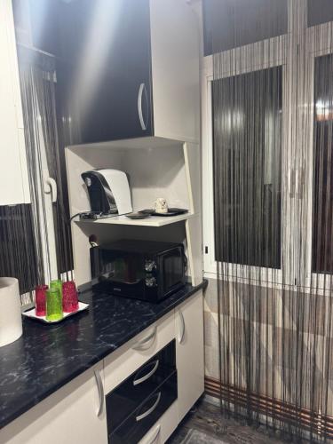 una cucina con piano di lavoro nero e forno a microonde di Walk-In Promenada a Craiova