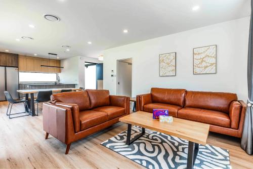 a living room with two leather couches and a table at Remarkable Cross Road Retreat in Frankton