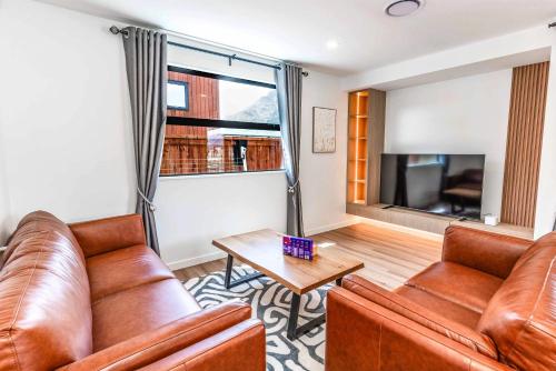 a living room with leather furniture and a large window at Remarkable Cross Road Retreat in Frankton