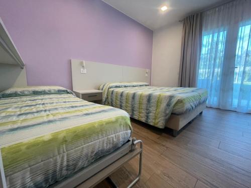 2 bedden in een kamer met paarse muren bij Il Fiore del lago in Pacengo di Lazise